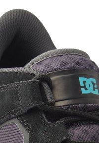 Black suede sneaker featuring a textured gray mesh upper, lace-up design, and a turquoise DC logo accent on the ankle.