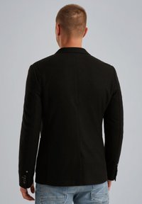 Zwarte op maat gemaakte blazer met een gladde textuur, gestructureerde schouders, één achterventilatie en knoopaccenten op de mouwen. Draag het over lichte jeans.