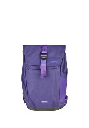 Mochila morada con cierre enrollable, correa de hebilla frontal, bolsillo lateral y logo "evoc" en la solapa superior.