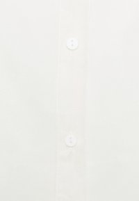 White button-down shirt featuring a smooth fabric texture and two white buttons at the center. Simple design with no additional patterns.