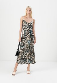 Leopard print maxi dress in shades of brown, black, and turquoise, featuring thin straps and a draped silhouette. Smooth fabric texture.