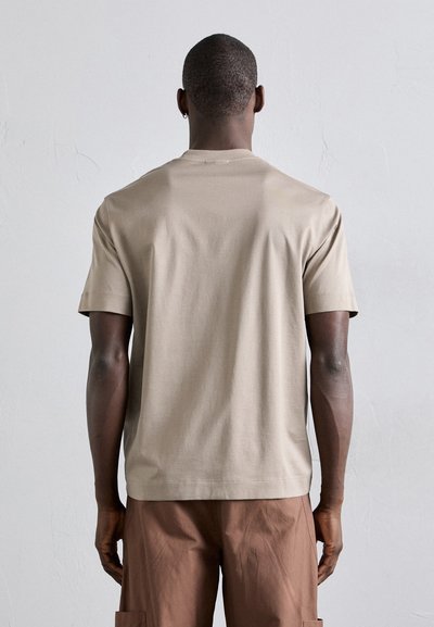 Beige kortermet T-skjorte laget av glatt bomull, med rund hals og ingen synlige logoer eller mønstre, vist fra baksiden.