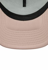 Gorra rosa con una tela suave, borde negro y costuras visibles. El interior es de color gris claro con una correa central negra.