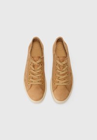 Sneakers in pelle color tan con occhielli dorati e lacci beige, dotati di punta arrotondata e superficie texture. Le solette sono etichettate "SUPER SOFT."
