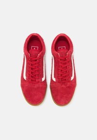 Sneakers in suede rosso con dettagli bianchi, lacci piatti e finitura testurizzata. Presentano suole in gomma naturale e un design aerodinamico.