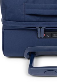 Maleta rodante azul marino con tela texturizada, doble cremallera, cerradura de combinación y asa retráctil para facilitar el transporte.