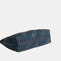 Sac matelassé rectangulaire en denim bleu avec garniture en cuir bleu foncé et quincaillerie dorée posé sur une surface plane.