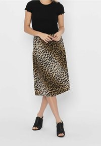 Sort ribbet t-shirt med korte ærmer, parret med en leopardmønstret midi-nederdel i nuancer af brun og beige; åbent tå sorte højhælede sandaler.