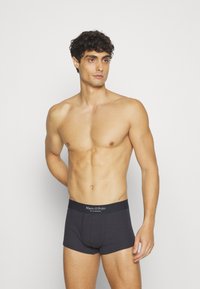 Tummanharmaat boxerit, joissa on pehmeä rakenne ja merkkivaijeri. Muotoilu on tiukka, mikä antaa virtaviivaisen ilmeen.