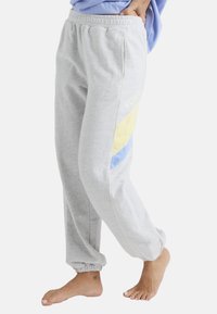 Grå sweatpants lavet af blødt stof, med gule og blå sidepaneler, elastiske manchetter og mærket "ROXY" i hvidt på siden.