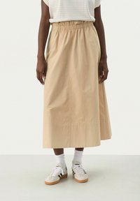 Knee-length beige skirt made of lightweight fabric, featuring an elastic waistband and a subtle seam detail along the hem.