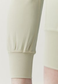 Bežové, elastické capri legíny s priliehavým strihom a zhušťovacími detailmi na leme, s plochými švami pre pohodlie.