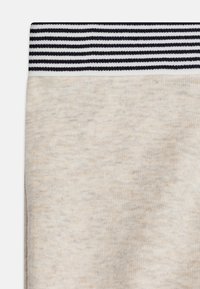 Světlý béžový látkový pás, s texturovaným povrchem. Pas je tmavě modrý s vodorovnými bílými pruhy.