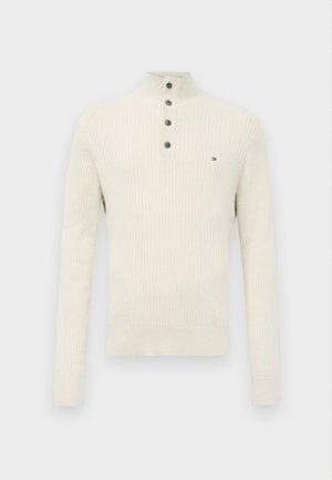 Crème ribbelgebreid sweater met lange mouwen, knoopsluiting op hoge kraag en klein logo op de linkerborst.