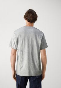 Harmaa puuvillapaita, jossa on lyhyt hiha ja pyöreä pääntie. Sujuva rakenne, rento malli, siisti muotoilu ilman koristeita tai kuvioita.