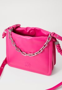 Ροζ δερμάτινη τσάντα χειρός με απαλό υφιστάμενο, αλυσίδα ως διακοσμητικό, λεπτομέρεια λογότυπου και ρυθμιζόμενο λουρί. Έχει μαλακή, σγουρή κορυφή για κλείσιμο.