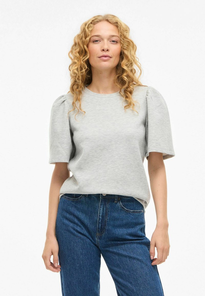 Pull-over gris à manches courtes bouffantes, confectionné dans un matériau doux ; assorti à un pantalon en denim bleu. Coupe simple et décontractée.