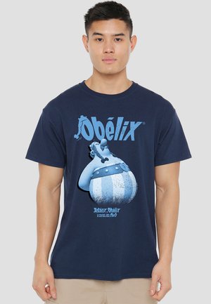 Navy blue cotton t-shirt featuring a graphic of Obélix, with bold blue lettering and a cartoonish design, including striped details on the character.