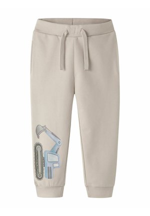 Beige børnesweatpants med elastisk talje, snor, manchetter og en blå gravemaskine grafik på venstre ben nær anklen.