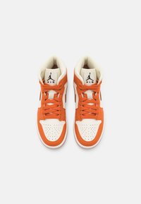 Paire de baskets montantes Nike Air Jordan blanches et orange vif, vues de dessus avec les lacets noués.