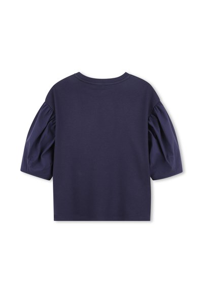 T-shirt bleu marine à manches courtes avec des manches bouffantes, fabriqué en tissu doux. Il présente un col rond et une coupe décontractée, sans détails supplémentaires.