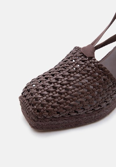 Chaussure marron tissée à bout fermé avec une semelle épaisse tressée et une bride à la cheville, mettant en valeur un motif texturé détaillé et une construction robuste.