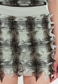 Adīta svārku kleita ar tekstūrētu rakstu ar zigzagampīpu gaismas piparmētru un tumši brūnās krāsās, pabeigta ar ribotu jostas daļu.