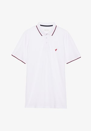 Polo blanc avec des bordures rouges et un petit logo rouge sur le côté gauche de la poitrine. Il dispose d'un col traditionnel et d'un plastron à trois boutons.