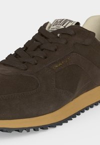 Baskets en daim marron avec semelle texturée, lacets marron et marquage "GANT" sur le côté et sur l'étiquette de la languette.