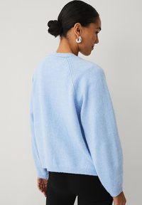 Pull bleu clair à coupe décontractée, ourlets côtelés et encolure ronde. Confectionné dans une maille douce et texturée.