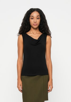 Top negro sin mangas con un escote drapeado, hecho de una tela suave. Combinado con una falda verde, que presenta un dobladillo recto.