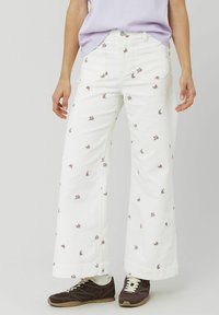 Jean large blanc avec broderie florale dans des nuances de rose. Fabriqué en coton, avec des poches avant et une fermeture à bouton classique.