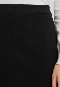 Schwarzer Wollmischrock mit einer glatten, strukturierten Oberfläche. Hat eine hohe Taille und ein einfaches Design ohne sichtbare Beschläge oder Muster.