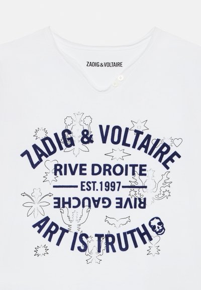 T-shirt en coton blanc avec un col en V, mettant en avant du texte imprimé en bleu foncé et des éléments graphiques, incluant des fleurs et un crâne, soulignant un design décontracté.