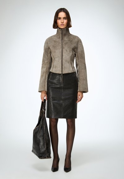 Siva kratka jakna od antilopa s visokim ovratnikom, širokim rukavima, crna kožna olovka suknja, crne hulahopke i velika crna kožna torba.