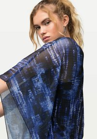 Cover-up in stile kimono blu e nero in tessuto trasparente con motivi astratti, caratterizzato da maniche larghe e scollo rotondo.