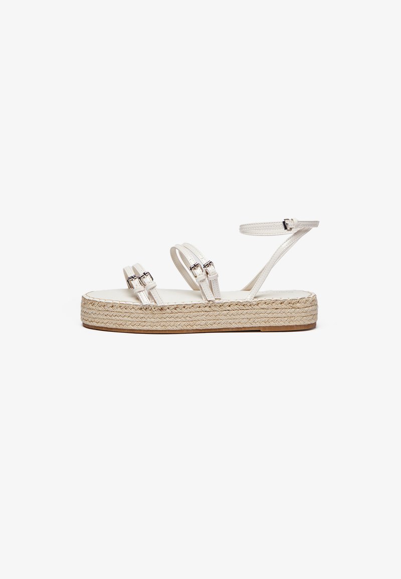 Witte platform sandalen met twee verstelbare banden met zilveren gespen, een geweven jute zool en een glad bovenmateriaal.