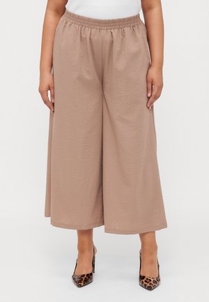 Pantaloni a gamba larga color marrone chiaro con vita elasticizzata, realizzati in un tessuto testurizzato. Abbinati a tacchi a punta con stampa leopardata.