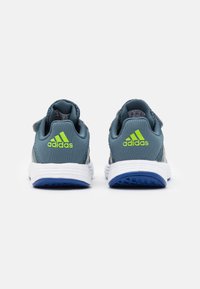 Blauwe en grijze sport schoenen met een witte tussenzool, een textiele bovenkant, contrasterende groene accenten en een flexibele rubberen buitenzool.