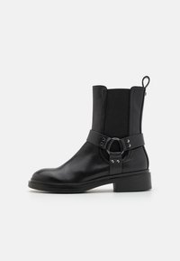 Black leather ankle boot featuring elastic side panels, a decorative band with a circular metal accent, and a low block heel.