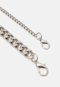 Catena in metallo argento con grandi anelli a un'estremità e una catena con anelli più piccoli dall'altra, ciascuna dotata di chiusura a moschettone.
