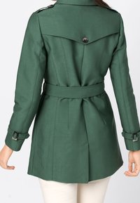 Zielony płaszcz trencz o dopasowanym kroju, z paskiem w talii, zapięty na guzik na pagonach oraz gładką fakturą. Posiada rozcięcie z tyłu.