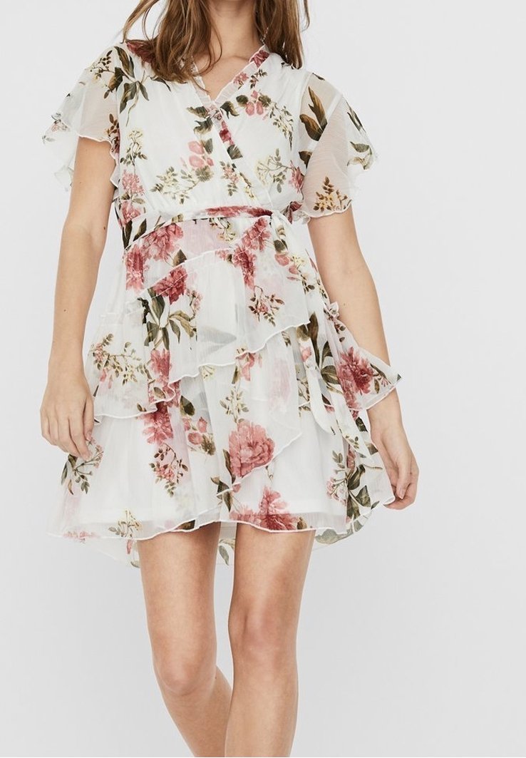 Kukallinen mekko, jossa on läpikuultavaa valkoista kangasta, rypytettyjä kerroksia, lyhyet hihat ja kääntödesign, jossa on vaaleanpunaisia ja vihreitä kukkakuoseja.