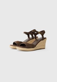 Brown suede wedge sandals with open toe, crossed ankle straps, and braided jute heel. Features a small gold buckle accent.