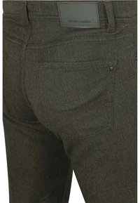 Donkergroene denim jeans met contrasterende stiksel, voorzien van achterzakken en een leren logoplaatje op de tailleband. Gestructureerde stof.