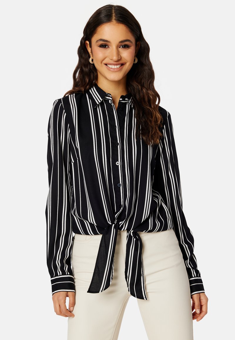Zwart-wit gestreepte blouse met knopen en een gestrikte voorkant, gemaakt van een gladde stof. Heeft lange mouwen en een klassieke kraag.