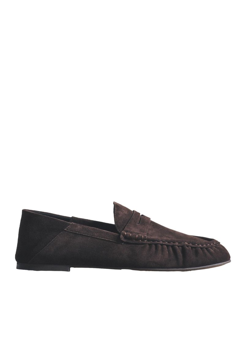 Mocassin en daim brun foncé avec un petit talon et des coutures mocassins le long du bout arrondi et des côtés.