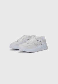 Zapatillas deportivas blancas con parte superior texturizada, detalle de logo y suela acolchada. Presentan cordones redondos y un diseño suave y ligero.