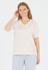 Lichtbeige V-hals T-shirt met korte mouwen, gemaakt van soepele stof, gecombineerd met grijze joggingbroeken met een klein logo nabij de zoom.