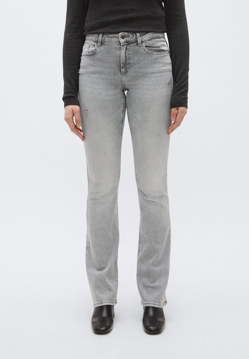 Ανοιχτό γκρι τζιν παντελόνια με εφαρμοστή μέση, ελαφριά φθορά και φαρδιά πόδια. Κατασκευασμένα από υφασμάτινο τζιν, διαθέτουν πέντε τσέπες και κουμπωτό κλείσιμο.